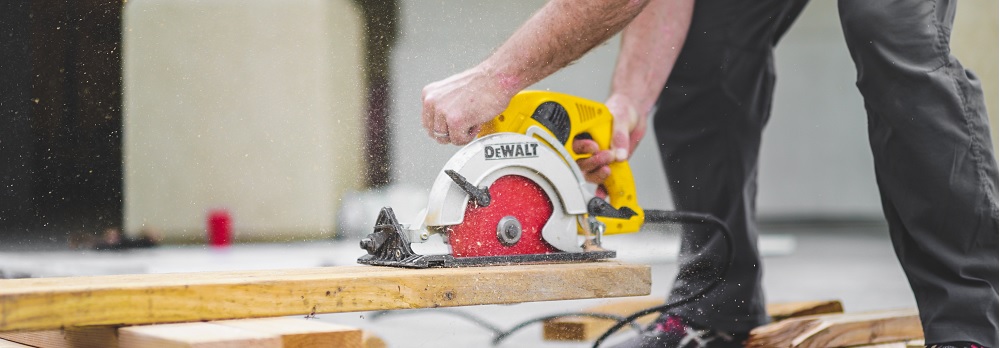 Een afbeelding van een persoon die in hout zaagt